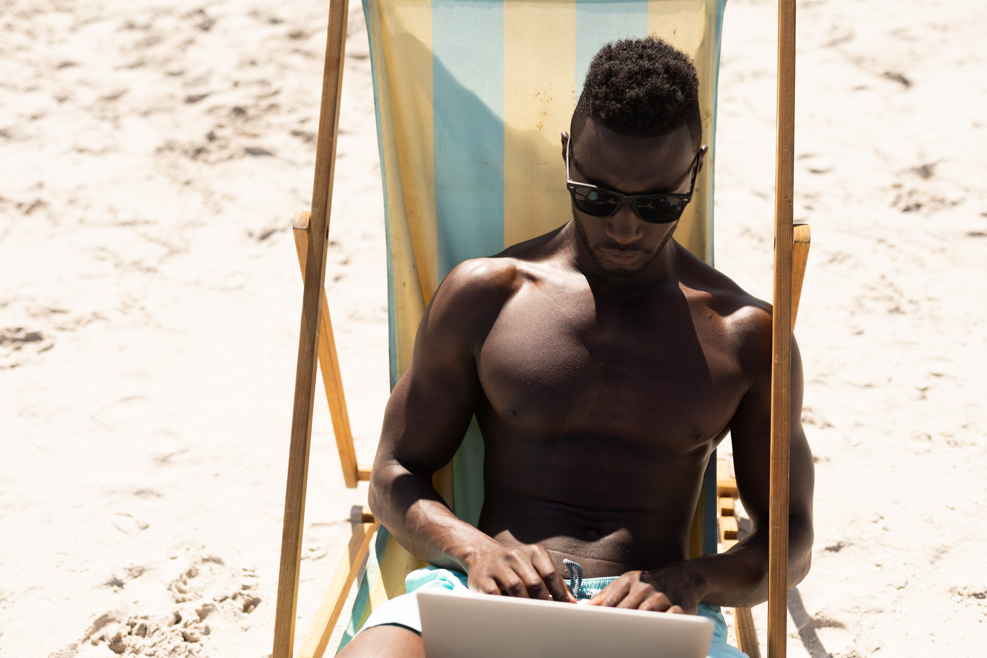 African American man using computer on the beach